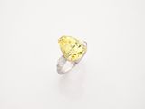a close up of a yellow diamond ring on a white surface