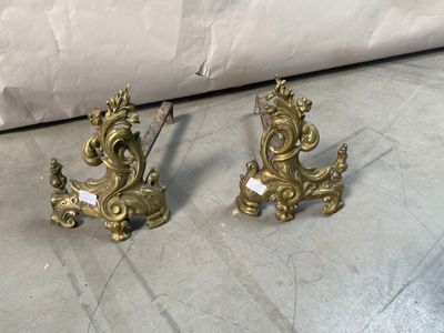 two gold colored candlesticks on the floor next to a couch