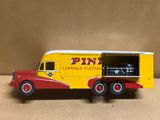 camionnetto jaune et rouge avec la portière ouverte, posé sur une surface beige clair