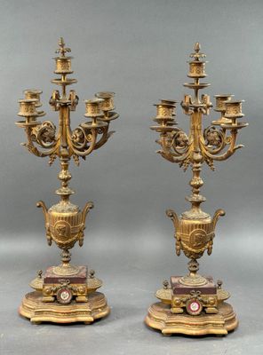 une paire de candélabres anciens en laiton, chacun muni d'une horloge