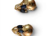 two pairs of gold and sapphire earrings on a white surface