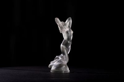a glass sculpture of a man on a black surface