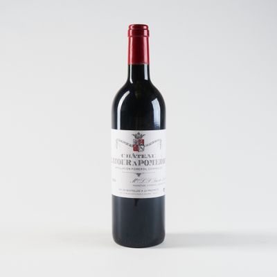 a bottle of red wine sitting on top of a white table