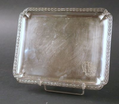 un plat ancien en argent posé sur un socle, sur fond noir