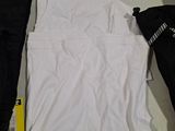 two pairs of black and white pants and a white t - shirt on a table