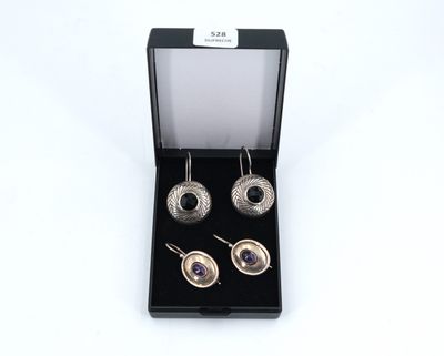 une paire de boucles d'oreilles dans un écrin noir sur fond blanc