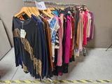 beaucoup de vêtements suspendus à une étagère dans une pièce