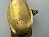 a close up of a gold watch on a white surface