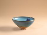 un petit bol bleu posé sur une surface blanche