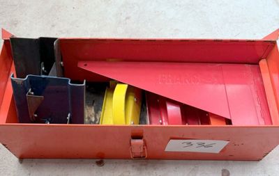 une boîte rouge posée par terre et remplie d'objets divers