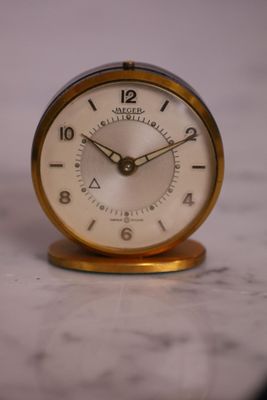 une petite horloge posée sur un plan de travail en marbre