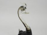 une figurine de cygne en verre noir et blanc posée sur une surface blanche
