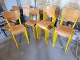 Six chaises en bois sont alignées contre un mur dans une pièce.
