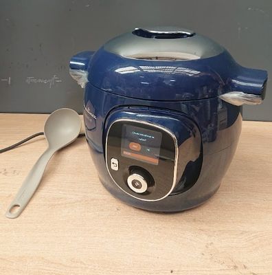 a blue electric pressure cooker with a spoon next to it