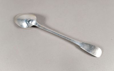 une cuillère en argent avec un manche de cuillère sur une surface blanche