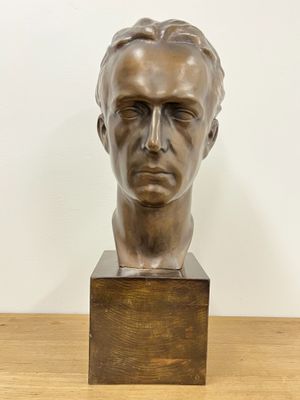 bronze bust of a man on a wooden base on a table