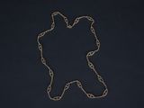 a silver chain with a bear on it sitting on a black surface