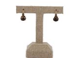 a close up of a pair of earrings on a stand on a white background