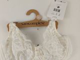 a close up of a white bralette on a hanger on a wall
