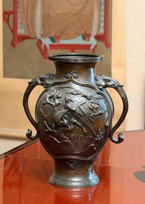 a bronze vase sitting on a glass table in a room