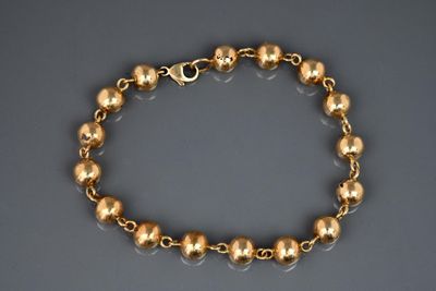 a close up of a gold bracelet on a gray surface