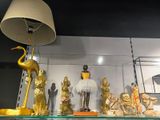 a glass shelf with gold statues and a lamp on it