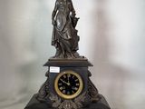 une statue de femme tenant une horloge sur une table