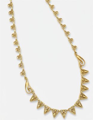 un collier plaqué or orné de pointes sur fond blanc