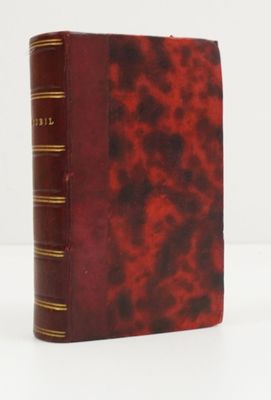 un vieux livre à la couverture rouge posé sur une table blanche