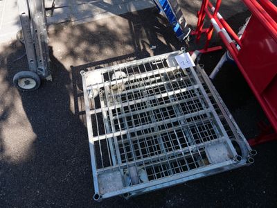 a metal cage on the ground next to a red cart