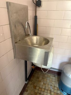 a stainless steel sink in the corner of a public restroom