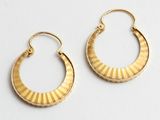 une paire de boucles d'oreilles en or posées sur une surface blanche