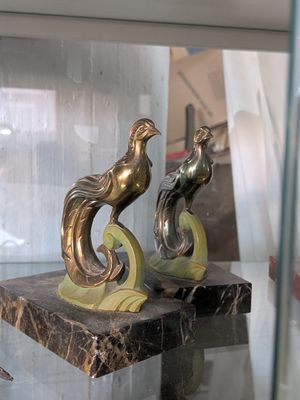 deux statues représentant un oiseau, posées sur un socle en marbre