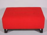 a red ottoman with black legs on a white background