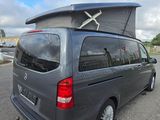 a grey van with a surfboard on top of it