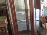 a tall wooden cabinet with a glass door in a room