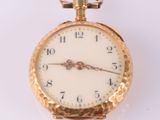 une montre de poche en or avec un cadran blanc sur une surface blanche