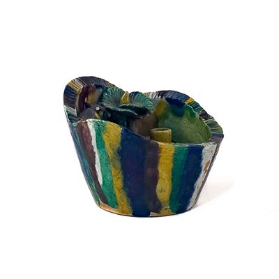 un bol coloré contenant une cuillère, posé sur une surface blanche