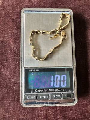 une balance surmontée d'une chaîne en or, posée sur une surface marron