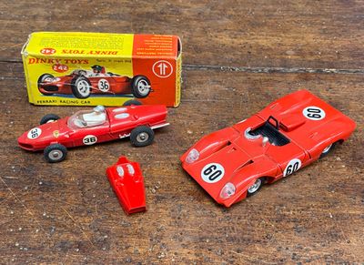 une petite voiture rouge à côté d'une autre petite voiture rouge, posées sur une table en bois