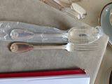 des couverts en argent posés sur une table, à côté d'une tasse de café