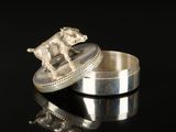 a silver ring with a dog on it on a black surface