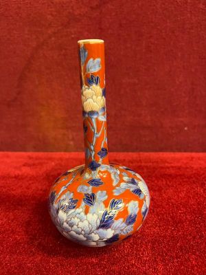 an orange and blue vase sitting on top of a red surface