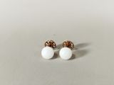 une paire de boucles d'oreilles en perles blanches posées sur une surface blanche