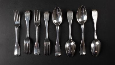six forks and six spoons arranged in a row on a black surface