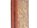an old book with a red cover sitting on a white surface