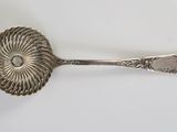 silver plated spoon with a flower design on it on a white surface