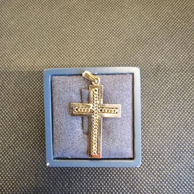 pendentif en forme de croix plaqué or, présenté dans un coffret bleu sur fond gris