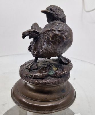 une statue en bronze représentant un oiseau perché sur une table en verre