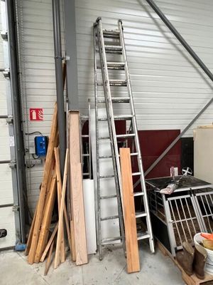 many pieces of wood and a ladder in a warehouse